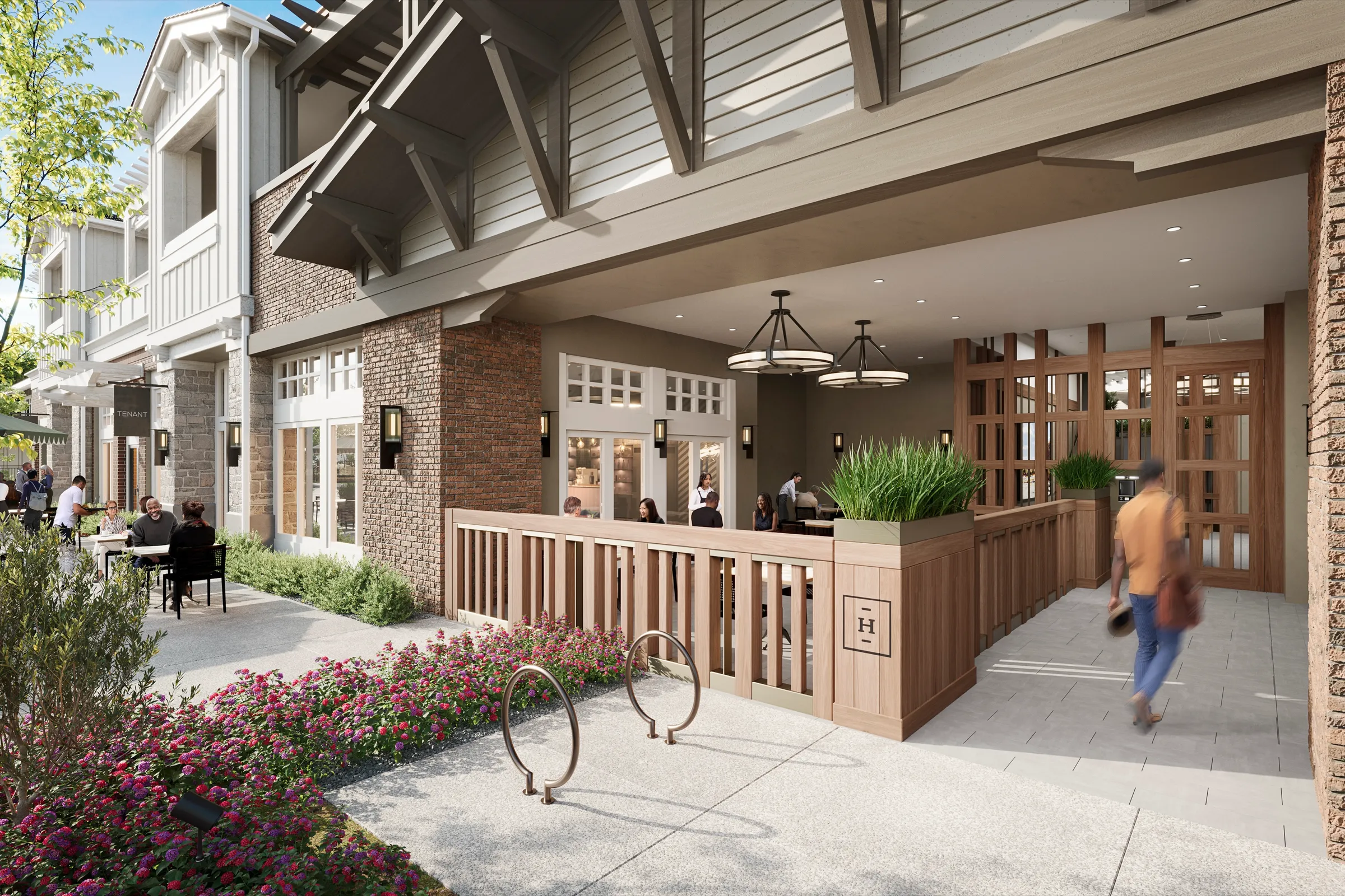 3D rendering of the covered open-air lobby entry at 600 Hartz Avenue in Danville, with timber railings, an H monogram gate, pendant lighting, brick detailing, and adjacent cafe seating.