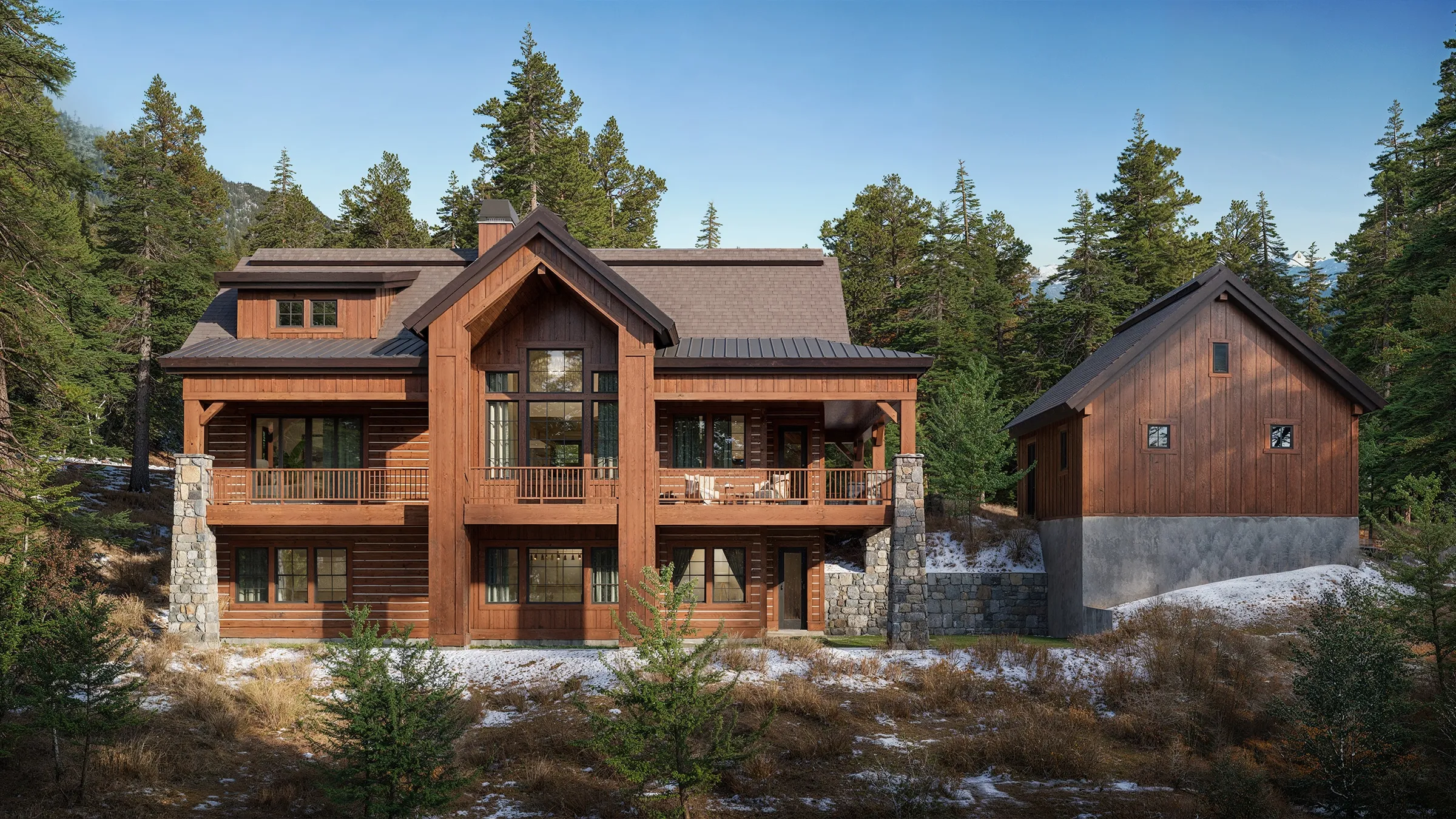 Photorealistic 3D rendering of the rear exterior of the Haystack model by Alturas Homes, a timber and stone mountain home with stacked covered balconies and a detached garage, surrounded by pines.