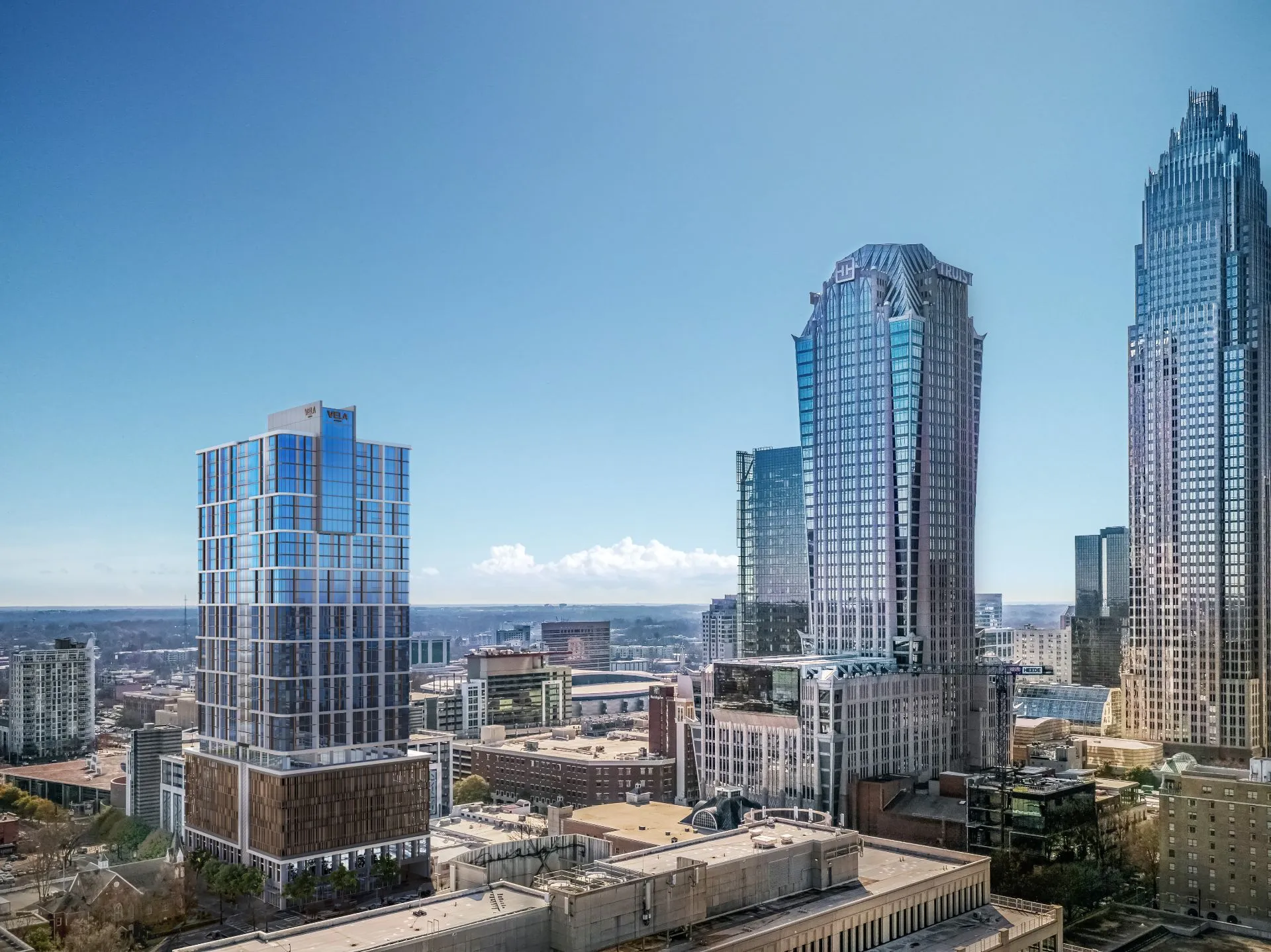 Aerial 3D rendering of the 32-story VeLa Uptown tower in Charlotte, a blue glass tower set among the city's skyline towers by day.
