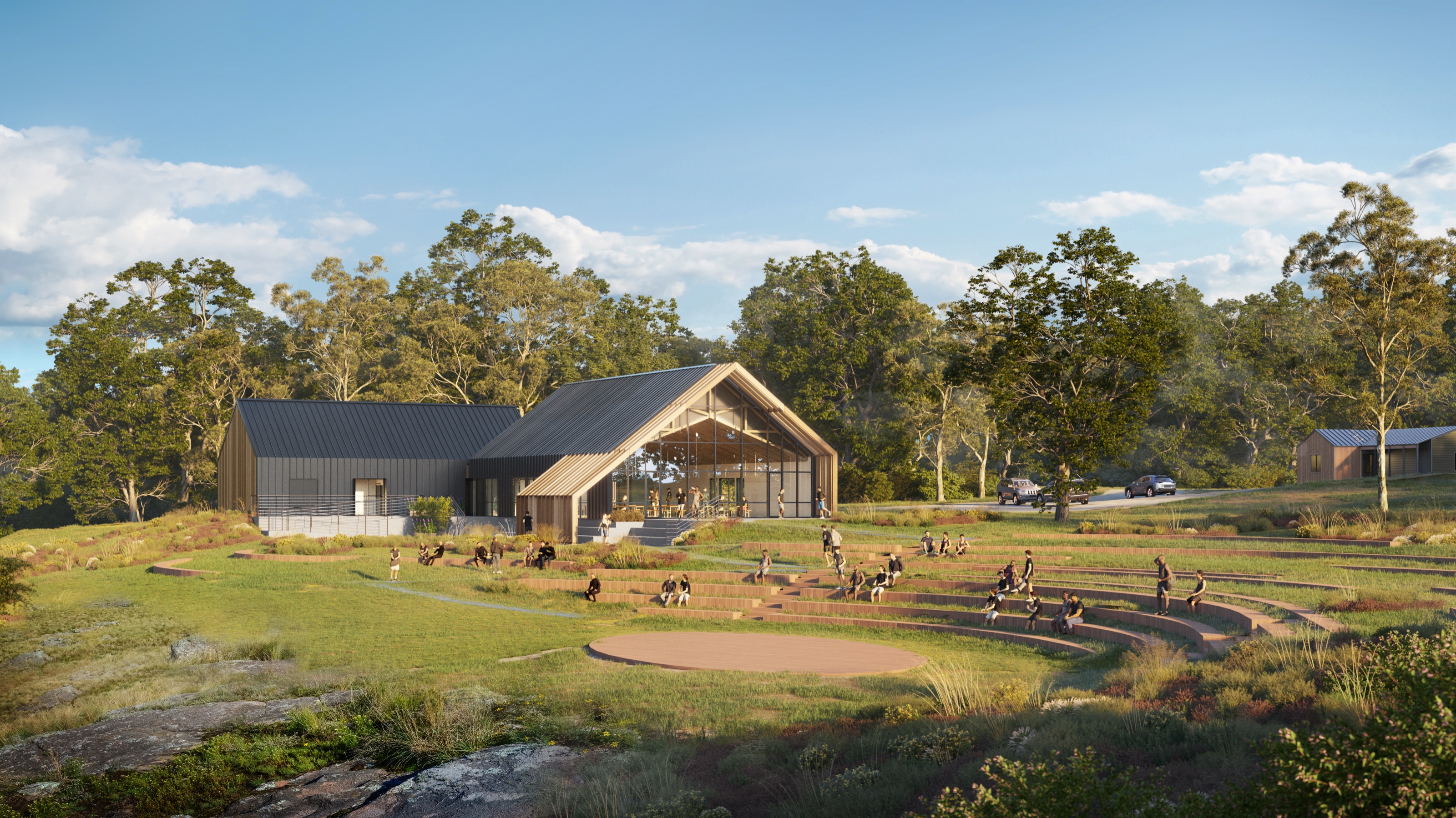3D rendering of the University of Health and Performance mess hall and its outdoor amphitheater, with people seated on timber terraces stepping down a meadow toward a circular packed-earth stage in late-afternoon light.